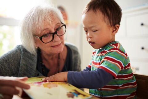 Eine Frau blättert mit einem Kind in einem Bilderbuch (Foto: Lebenshilfe/David Maurer)